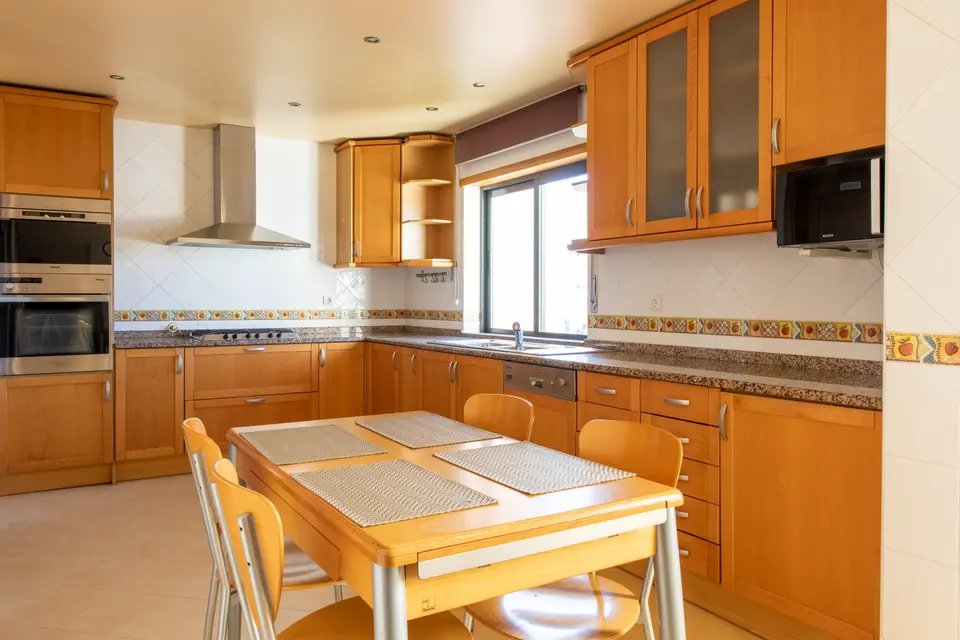 Shared kitchen with wooden cabinets and a large dining table.