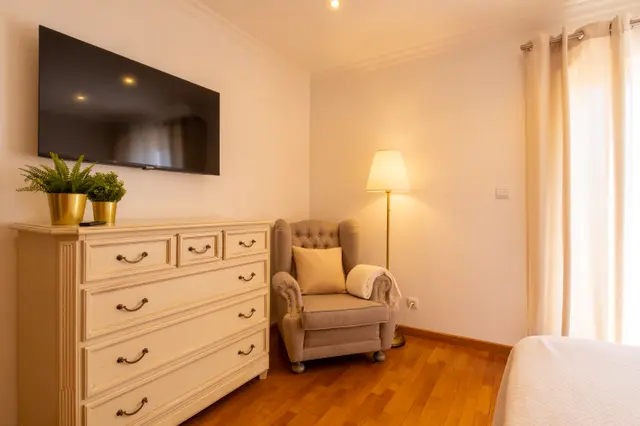 Armchair and floor lamp beside the chest of drawers and TV.
