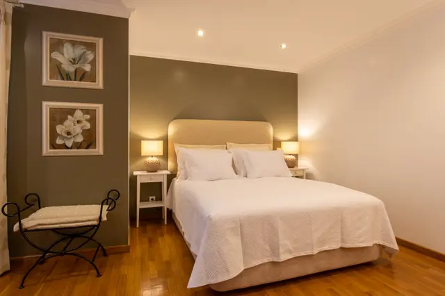 Double bed with beige headboard against an olive green wall.