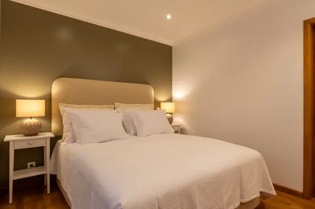 Angled view of the double bed and bedside lamp.