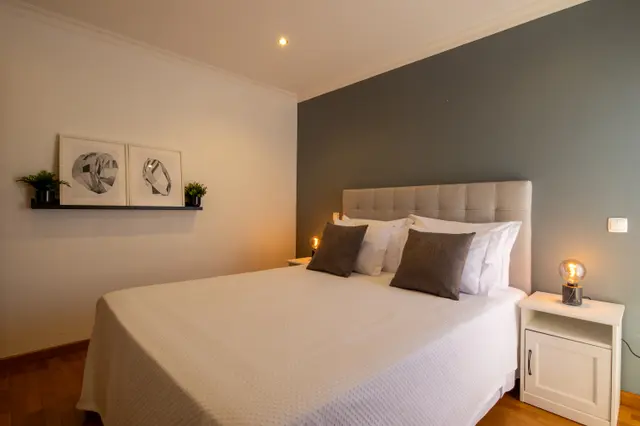 Bedroom with double bed and framed prints on a shelf.