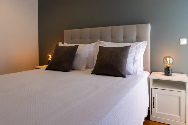 Large double bed with tufted headboard and bedside lamps.